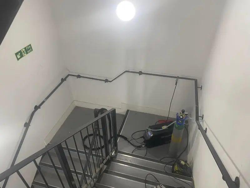 Black steel handrail and balustrade fixed around a white-walled stairwell