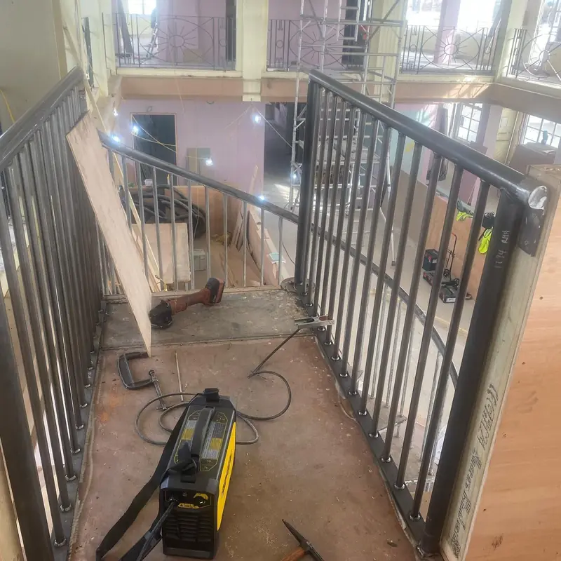 Black steel balustrade panels lining a walkway inside a building under refit